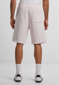 Lys rosa sweatshorts med elastisk linning, med en baklomme og en avslappet passform, laget av mykt bomullsstoff.