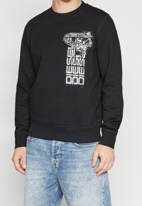 Sudadera negra con cuello redondo, con un estampado gráfico en azul y blanco en la parte frontal, y puños y dobladillo acanalados.