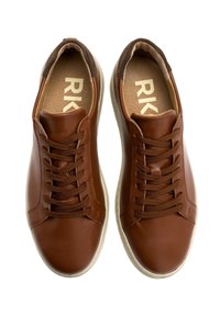 Bruna lädersneakers med runda tår, som har en texturerad yta, mörkbruna detaljer och platta snörningar. Logotyp synlig på innersulorna.