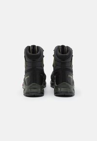 Black hiking boots with green accents, textured high-top design, reinforced heel, and durable rubber sole. No visible branding on the back.
