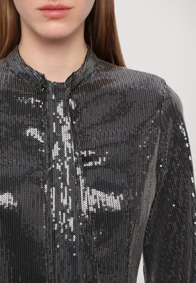 Top nero con paillettes, caratterizzato da un colletto alto e una chiusura frontale, con una texture liscia e un motivo superficiale scintillante.
