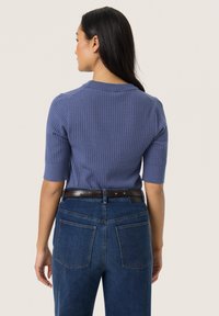 Light purple ribbed sweater with short sleeves, featuring a round neckline. Paired with high-waisted blue denim jeans and a brown belt.