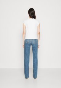 Witte korte mouwen t-shirt gecombineerd met lichtblauwe rechte jeans, met gestikte zakken en een lichte slijtage aan de zoom.