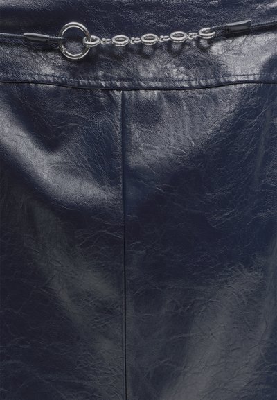 Jupe en cuir bleu marine foncé avec détail de couture devant et ceinture chaîne argentée avec maillons ovales entrelacés et fermoir circulaire.