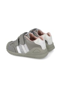 Zapatos infantiles grises con dos correas de velcro, acentos brillantes y una suela texturizada. Los detalles en plata y rosa realzan el diseño.