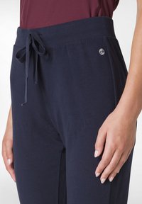 Marina blå sweatpants med dragsko i midjan, mjukt tyg och en liten logotyp på sidan, med avslappnad passform och minimalistisk design.