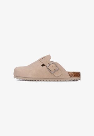 Chaussure mocassin en daim camel avec talon ouvert, fermeture latérale par boucle, semelle extérieure texturée camel et accent en liège sur le talon.
