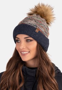 Berretto in maglia con parte superiore multicolore, base blu navy e pompon in pelliccia sintetica. Presenta un design testurizzato e un piccolo etichetta in pelle sul davanti.