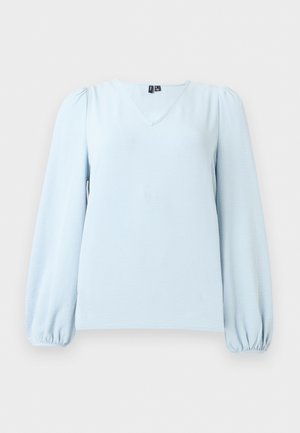 Blouse bleu clair à manches longues avec col en V et poignets froncés, présentée sur un fond neutre et à plat.