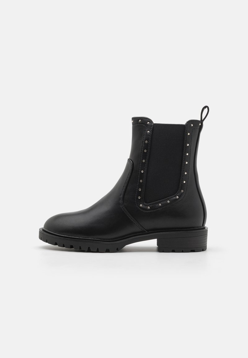 Bottines noires avec des panneaux latéraux élastiques, des accents cloutés et une surface texturée. Dotées d'un petit talon bloc et d'une semelle robuste.