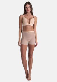 Reggiseno beige imbottito con scollatura a V profonda e spalline regolabili, abbinato a mutandine boyshorts beige semitrasparenti. Tessuto liscio, design aderente.
