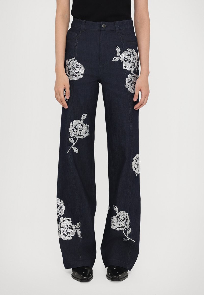 Donkerdenim wijde broek met zilveren bloemborduursels op beide benen, voorzien van een knoopsluiting aan de voorkant en zijzakken.