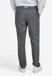 Pantalons à carreaux gris avec une coupe ajustée, dotés de deux poches arrière avec des fermetures à bouton et d'une texture lisse. Associés à des baskets blanches.