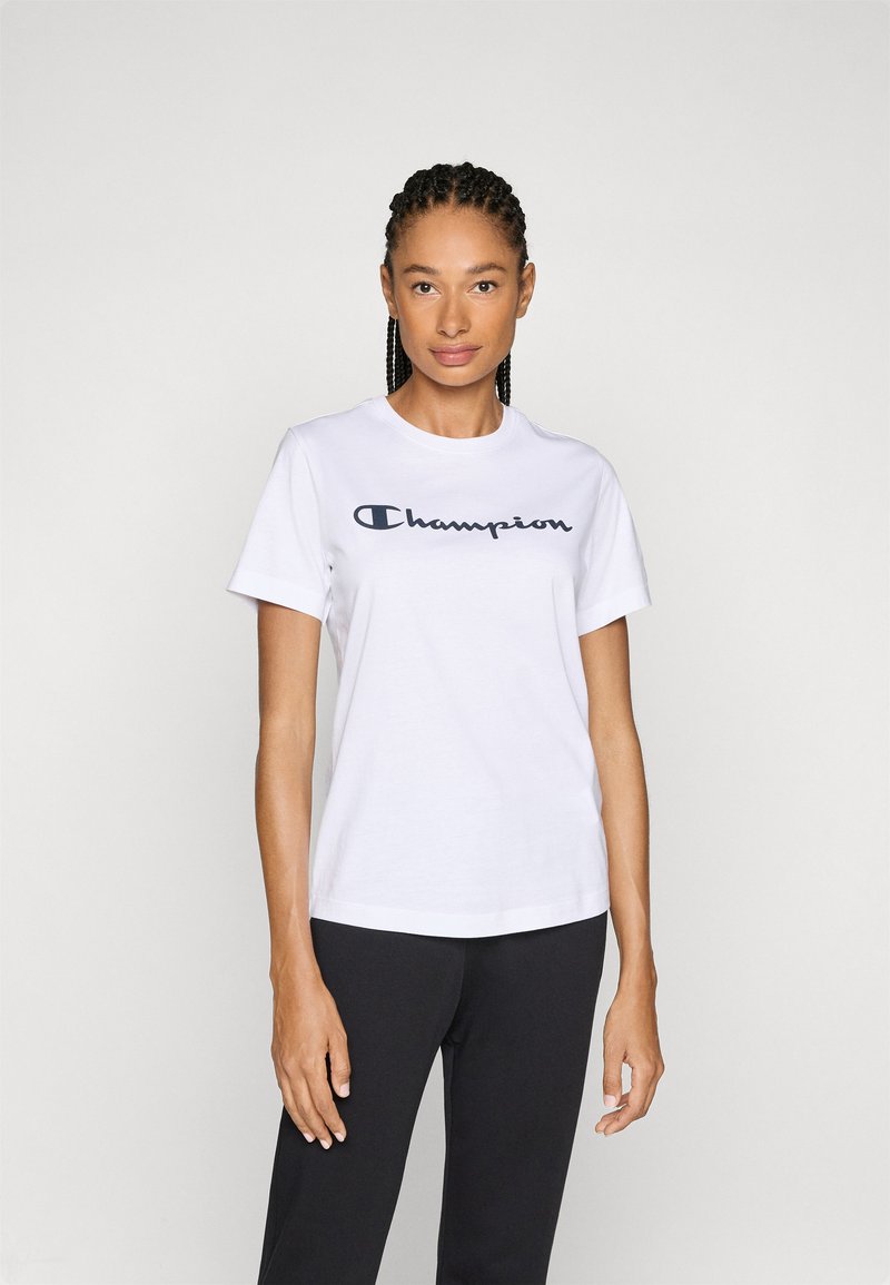 Weißes Baumwoll-T-Shirt mit einem marineblauen "Champion"-Logo in Schreibschrift auf der Brust. Kurze Ärmel und ein runder Ausschnitt.