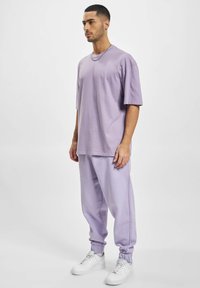 Lavendel katoenen oversized t-shirt en bijpassende sweatpants, met een elastische tailleband en boorden. Witte sneakers maken de outfit compleet.