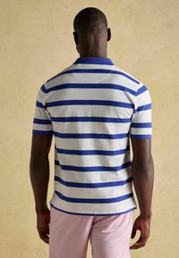 Helehall polo särk, millel on julged sinised horisontaalsed triibud, lühikesed varrukad ja krae, otse äärega ja pehme tekstuuriga.