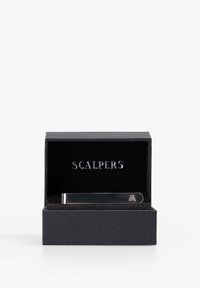 Clip de corbata plateado en una caja negra texturizada. Presenta un acabado pulido y un pequeño logo de calavera. Interior forrado con tela negra.