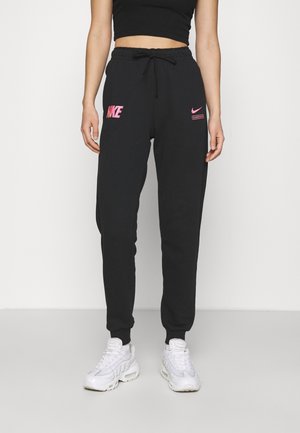 Slim-fit sorte Nike sweatpants med pink logo-accenter, båret med hvide atletiksneakers og en sort croptop.