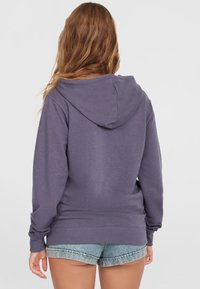 Paarse hoodie van zacht materiaal met een ontwerp voor het achteraanzicht. Heeft een ruime capuchon en ribbels aan de manchetten, gecombineerd met denim shorts.