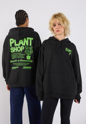I felpe nere con cappuccio presentano testo e grafiche in verde brillante sia sul retro che sul davanti, con una texture morbida e una tasca frontale.