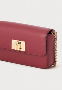 Maroon leather crossbody bag with a gold lock closure and a metal chain strap. Smooth texture with a rectangular shape and minimal stitching.