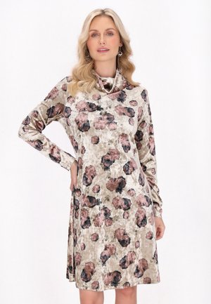 Kukallinen mekko pehmeästä, teksturoidusta kankaasta, jossa on pitkät hihat ja huppu kaula-aukko. Värit ovat beige, vaaleanpunainen ja musta, ja malli istuu rento.