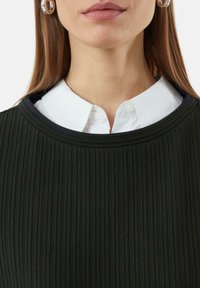 Black ribbed top with a wide neckline layered over a white collared shirt. Features large silver hoop earrings.