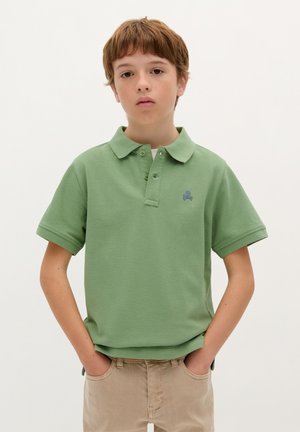 Polo shirt verde chiaro realizzato in tessuto testurizzato, con un logo a forma di teschio blu sul lato sinistro del petto, dotato di colletto classico e maniche corte.
