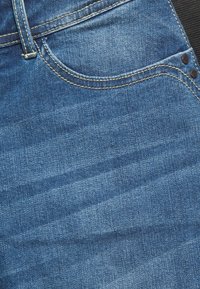 Denim jeans featuring a dark blue color, subtle textured pattern, and visible stitching details with a classic five-pocket design.
