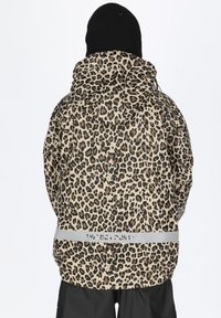 Leopardmuster wasserabweisende Jacke mit Kapuze, grauem Reflektorband und verstellbaren Zugbändern, kombiniert mit einer schwarzen Mütze.