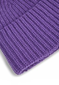 Close-up of a purple knitted fabric showing thick ribbed texture and detailed stitch pattern.