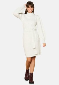 Knit sweater dress in light cream with a high neck, three-quarter puff sleeves, a belted waist, and a textured diamond pattern.