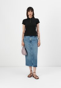 Zwarte poloshirt met gouden knopen, blauwe spijkerrok, bruine sandalen met bandjes en een kleine lavendelkleurige handtas.