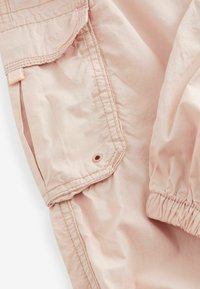 Lichtroze cargobroek met een gladde textuur, voorzien van een elastische tailleband, zijzakken en versterkte naden.