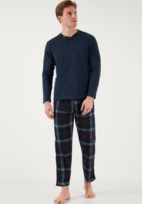 Pijama de manga larga en color azul marino con cuello redondo y acentos de botones rojos; pantalones de pijama a cuadros en azul marino, rojo y blanco con cinturilla elástica.