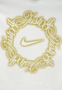 Λευκό ύφασμα με χρυσές γραφές που σχηματίζουν έναν κύκλο γύρω από το χρυσό λογότυπο Nike στο κέντρο.