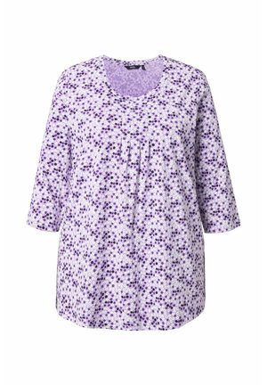 Túnica de algodón morada con escote redondo, mangas 3/4 y un patrón floral de puntos blancos y púrpura más oscuro. Textura suave con pliegues en la parte delantera.