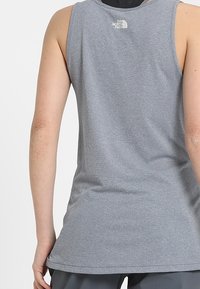 Szary bezrękawnik z teksturowanej tkaniny, z małym logo na górnej części pleców i prostym wykończeniem w talii.