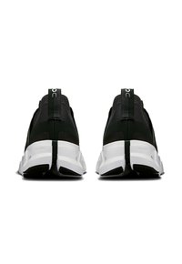 Chaussures de sport noires avec une tige en tissu texturé, un tirant distinct et une semelle intermédiaire blanche dotée d'une semelle en caoutchouc pour l'adhérence.
