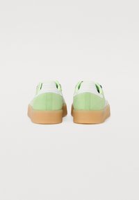 Grønne ruskind sneakers med hvide mesh-detaljer, gummisåler og polstret krave; har en glat overflade og rund form.