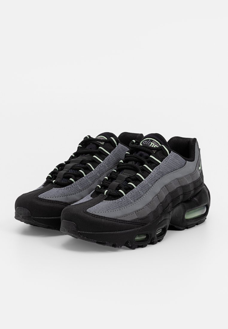 Baskets de sport noires et grises avec une tige en mesh, semelle rembourrée avec des poches d'air, lacets ronds et accents réflecteurs.