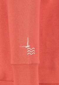 Korallenfarbener Pullover aus strukturiertem Stoff, mit einem weißen gestickten Vogel- und Wellenmuster auf dem Ärmel. Gerippter Bund am Saum.