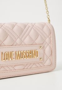 Geantă din piele roz matlasată, cu un placaj aurit "LOVE MOSCHINO" și cusături decorative. Include un lanț pentru umăr.