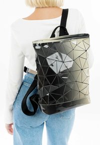 Zwarte rugzak met geometrisch patroon, gemaakt van glanzend materiaal, met een driehoekig ontwerp, verstelbare schouderbanden en een rits bovenkant sluiting.
