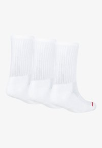 Trois chaussettes en coton blanc avec une texture nervurée, longueur mi-mollet, talon et orteil renforcés, et un petit accent rouge sur la cheville.