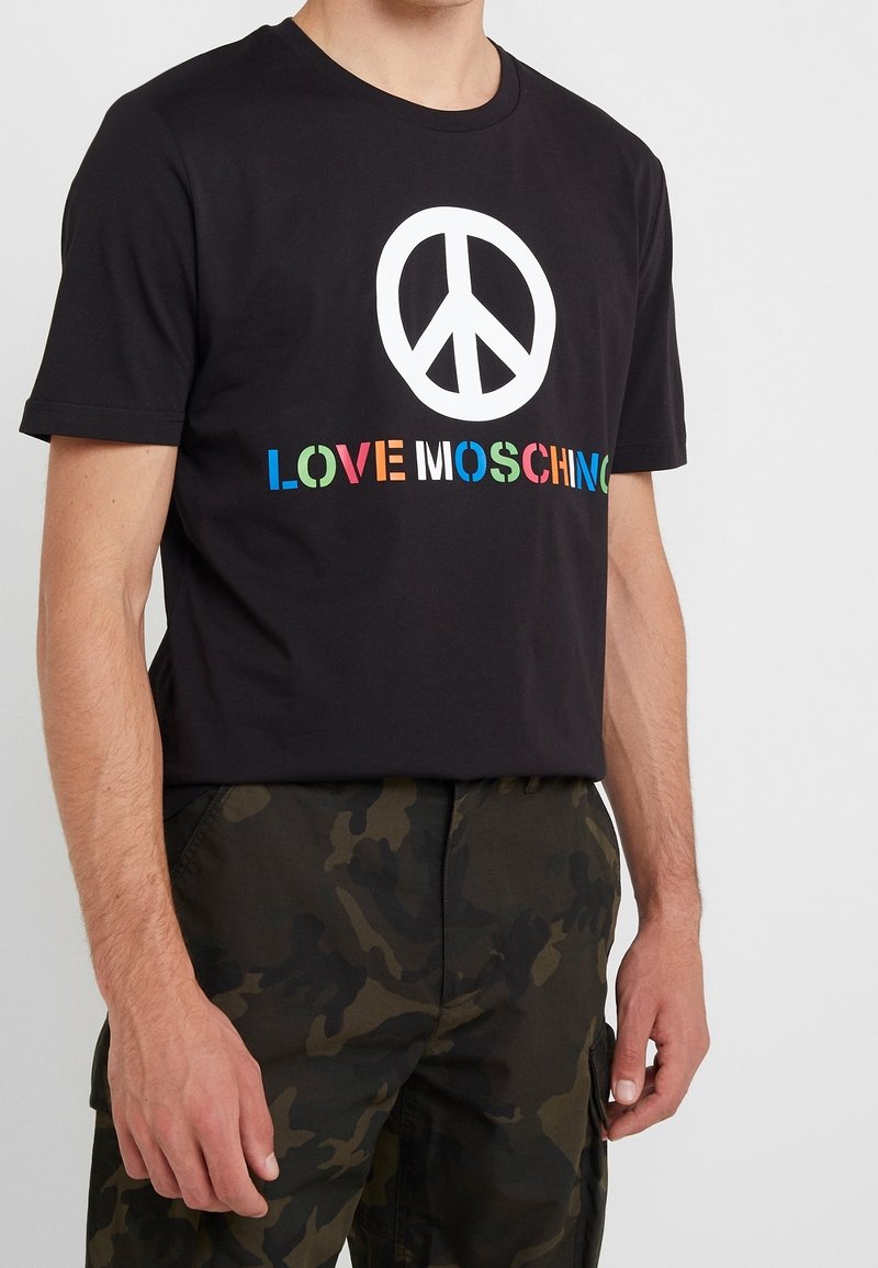 Zwart katoenen T-shirt met een groot wit vredessymbool en "LOVE MOSCHINO" in meerkleurige letters. Korte mouwen en ronde hals.