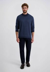 Navyblauer Strickpullover mit strukturiertem Fischgrätenmuster und Rundhalsausschnitt, kombiniert mit dunklen Chinos und braunen Slippern.