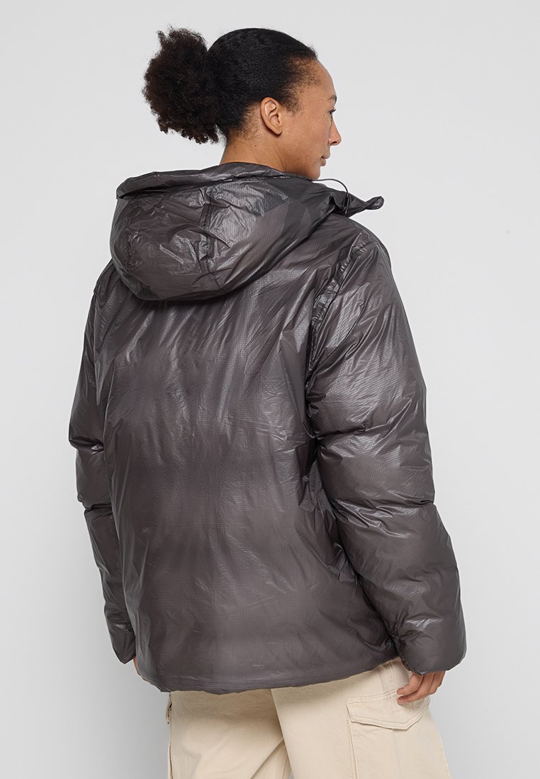 Giacca a vento imbottita nera e lucida con cappuccio, presenta un design trapuntato, cuciture visibili e una vestibilità comoda, realizzata in materiale leggero.