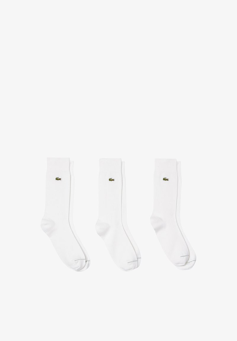 Three pairs of white cotton socks featuring a small green embroidered crocodile logo, with a smooth texture and classic crew design.