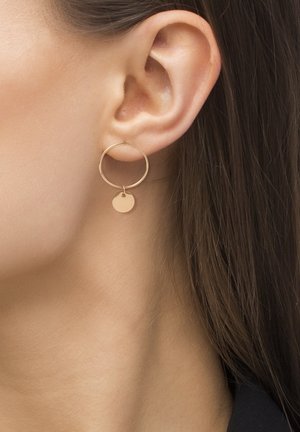 Goldene runde Creole mit einem angehängten kleineren Plättchen, das eine glatte Oberfläche und ein minimalistisches Design aufweist.